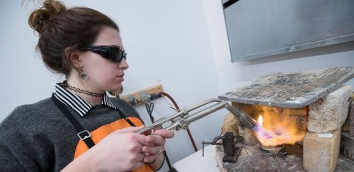 Student working on metalsmithing, using tools and fire