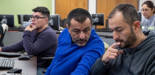 Adults working together on computers at RIC's Workforce Development Hub in Central Falls, RI