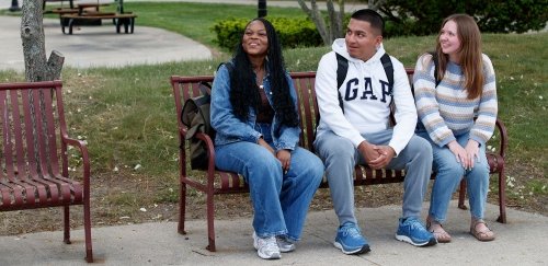 Students sitting together on bench, smiling