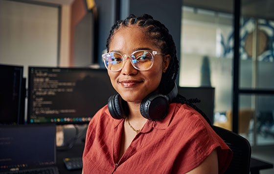 Person working in tech near monitors with headphones