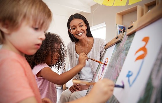 Young teacher admiring as children paint