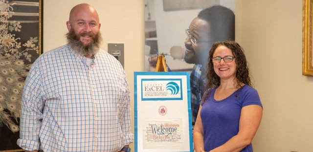 Brian Stevens (Left) and Laura Faria-Tancinco (right) standing next to a Project ExCEL poster 