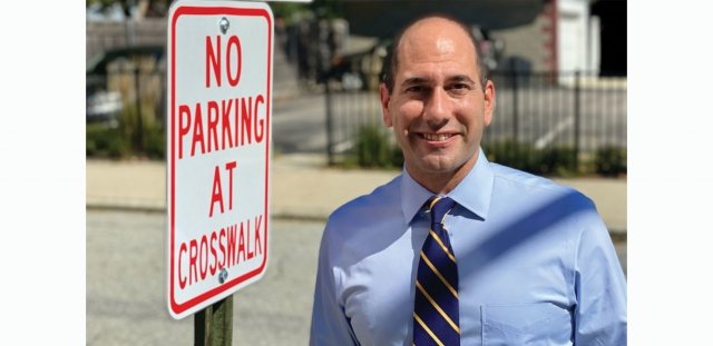 Providence City Councilor David Salvatore stands next to a "No parking at crosswalk" sign