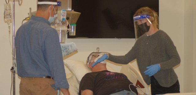 Two nursing students tend to a crisis actor in a hospital bed during a disaster simulation exercise