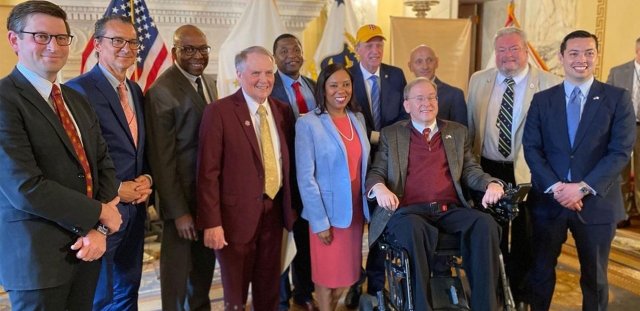 A large group of state leaders, including RIC President Warner, Gov. McKee and former Congressman James Langevin gather in the Governor's State Room at the RI State House.