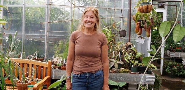 Pam Hill inside greenhouse surrounded by plants