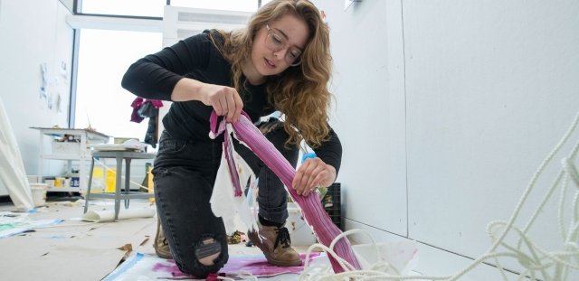 Jenna Deangelis, stretching a paint substance in the studio