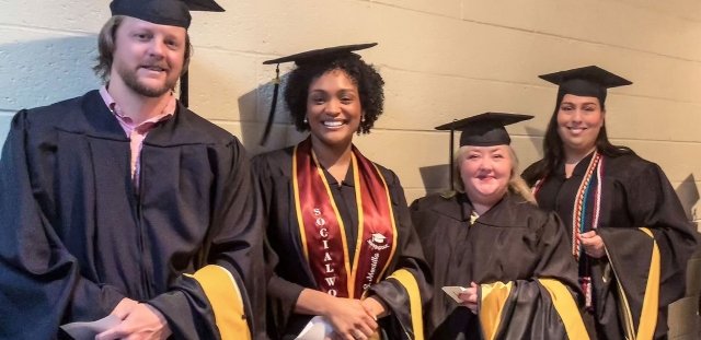 Four social work graduates in cap and gown
