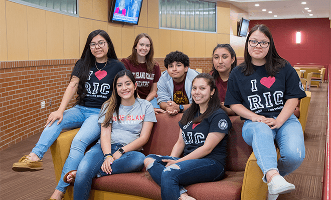 Group of students wearing RIC tee shirts happy in a residence hall 