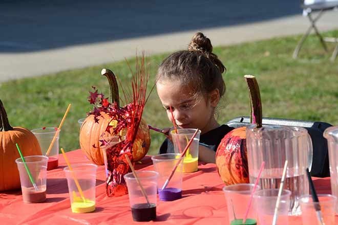 child painting pumpkin outdoors during the day