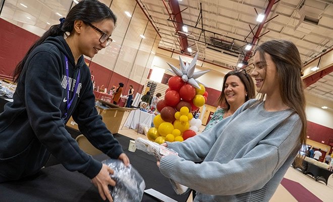 Student receives materials from person at Grad Fest