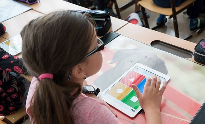 Young student selecting shapes in a classroom on an ipad