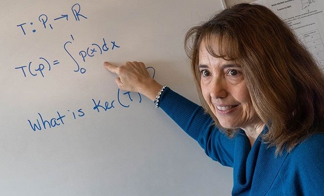 Math professor Lisa Humphreys at a white board, writing equations