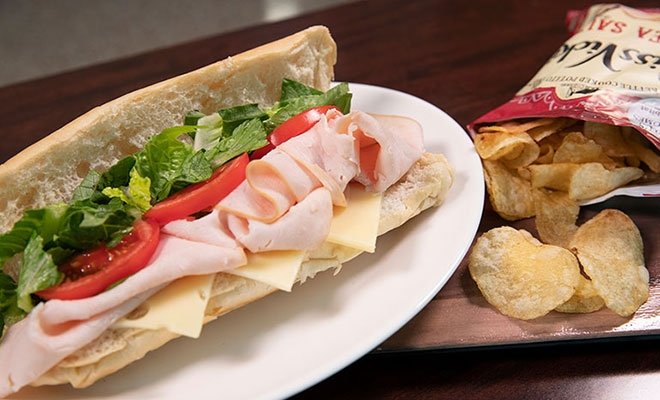 Turkey, cheese, lettuce, and tomato sub sandwich with bag of chips