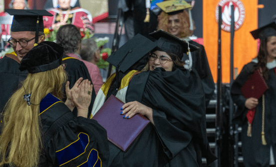 RIC Graduate hugging faculty member at commencement