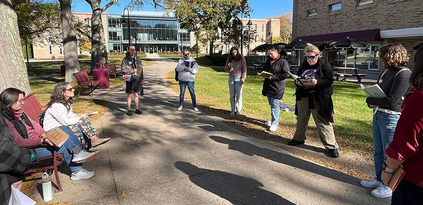 People on campus standing in circle with writing supplies